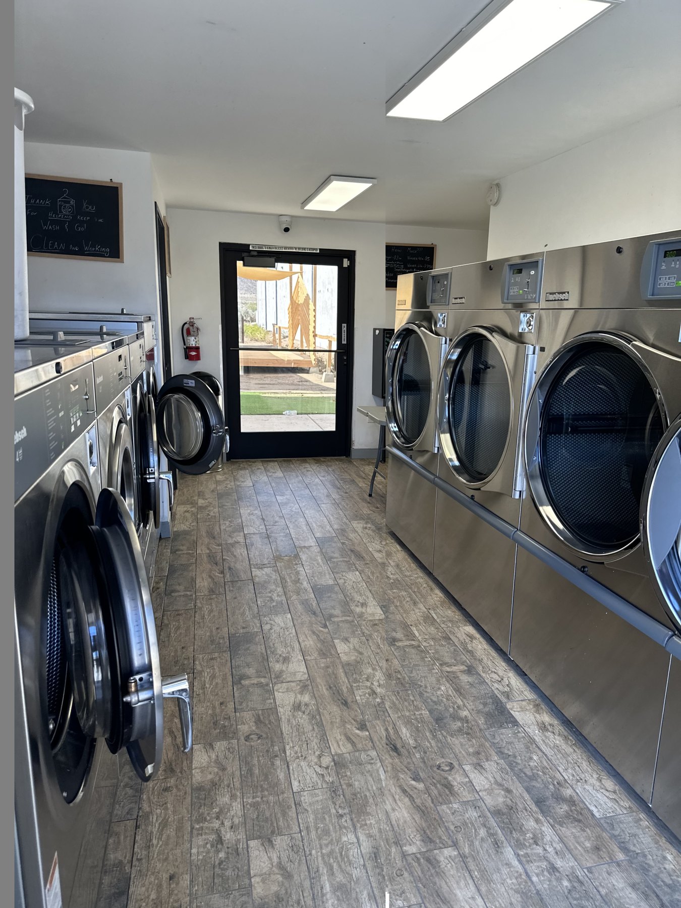 Large commercial washers and dryers inside Wash and Go Laundromat